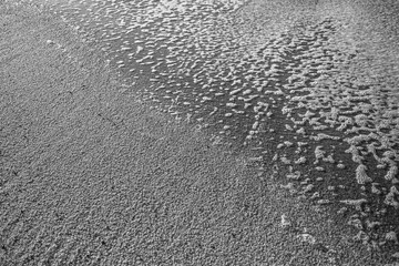 The beach sand with the foam of the surf Atlantic Portugal coasts. Black and white photo.