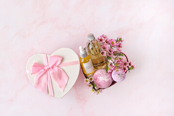 heart gift box with with spa treatments and pink flowers on pink marble background. festive spring season. 14 february, Valentine's day, romantic gift for women. top view. copy space