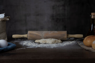 Dough and dough roller on a wooden surface.