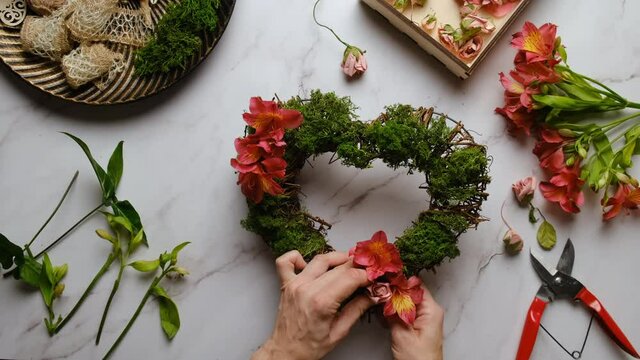 Florist decorates floral wreath for Valentines day. Hand crafted Valentines day home decor. Table top view, POV. 
