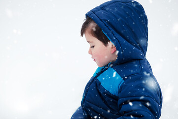 Adorable boy in winter jacket surrounded with snow. Wintertime, kids activity