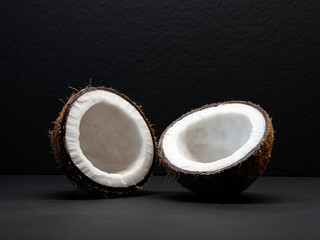 Coconut is divided in half on a black background