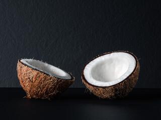 Coconut is divided in half on a black background