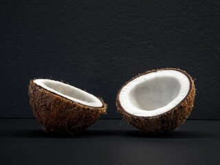 Coconut is divided in half on a black background