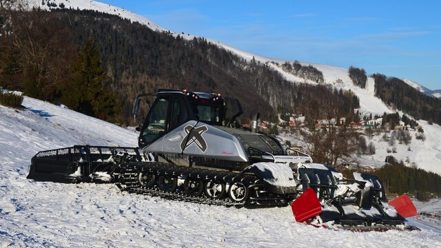 Side view of Prinoth LeitWolf snow groomer in silver metallic colour, parked in snow on top of ski slope in Donovaly ski resort Park Snow, central Slovakia, january 2022 winter season, afternoon sun.