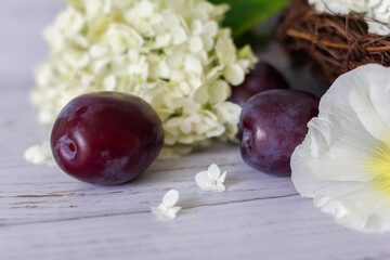 Ripe plums in a vine basket on a wooden background.