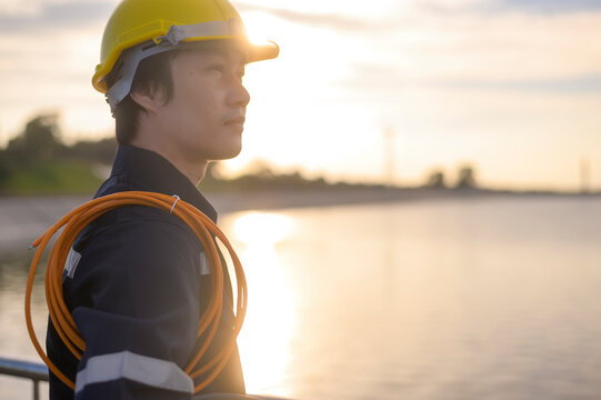 A male engineer wearing a protective helmet at sunset..