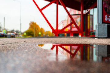 Autumn day in the city. Entrance to the mall. Reflection in a puddle on the asphalt. Close up view from the asphalt level.