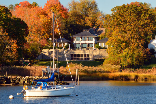 A Sailboat Is Moored Off Shore Of A Waterfront Mansion Inthe Wealthy Town Of Greenwich, Connecticut