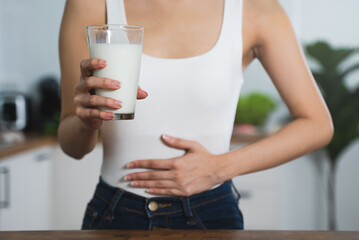 lactose intolerance concept. Woman holding a glass of milk and having a stomachache.