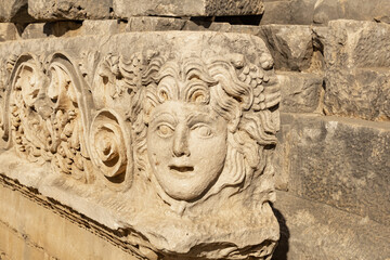 antique frieze with stone-cut mask in the ruins of the ancient city of Myra, Turkey