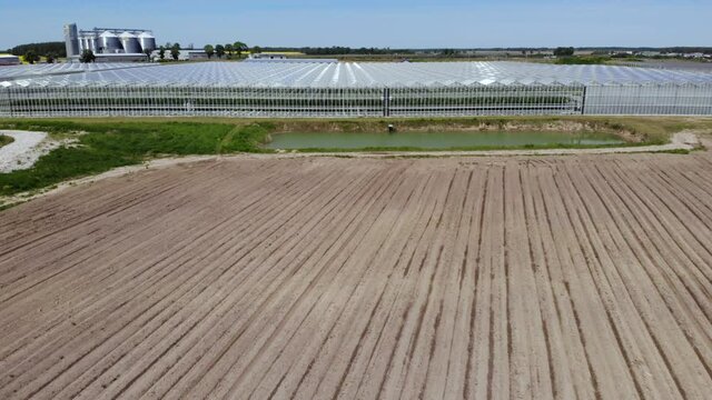 Greenhouse With Transparent Glass Roof Aerial View Flying Over Large Greenhouse With Vegetables. Modern High-tech Greenhouse View From Above. Aerial View Large Industrial Technology Greenhouses.