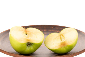 Two halves of a sweet green apple on a clay dish, close-up, isolated on white.