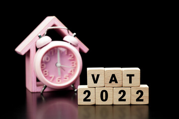 Vat Concept. Vat 2022 word is written on wood block and clock on black background.                          
