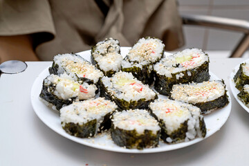 Homemade sushi, cut into pieces, are on the plates.
