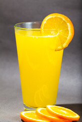 Glass of fresh orange juice with fruits cut in half and sliced isolated on gray background, clipping path