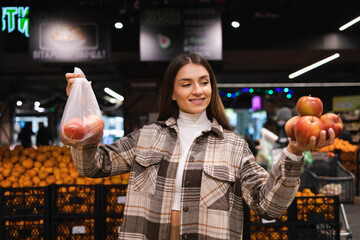 Eco friendly woman buys apples in the supermarket. Female grocery shopper opposes the use of plastic bags