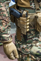 Pistol in holster on belt of an armed man.Multicam camouflage. Topic: weapon, armed man, gun, military patrol. Man in camouflage is armed with pistol