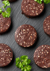 Raw Black Pudding with parsley on rustic stone board
