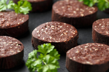 Raw Black Pudding with parsley on rustic stone board