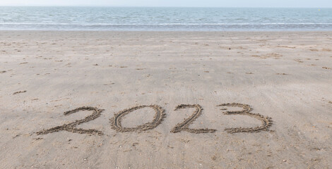 the text 2023 written in the sand on the beach