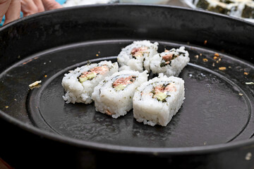 Sushi covered with rice lies on a baking dish.