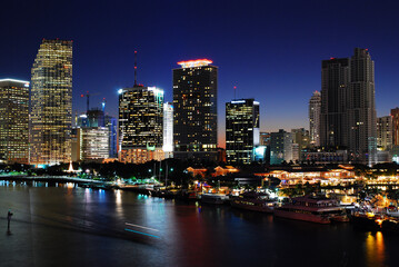 Obraz na płótnie Canvas A boat cruises the Intercostal Waterway in front of the Miami Skyline at night