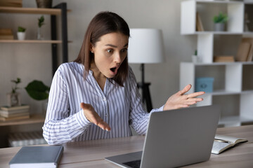 Stressed shocked computer user staring at laptop screen with open mouth in surprise, having...