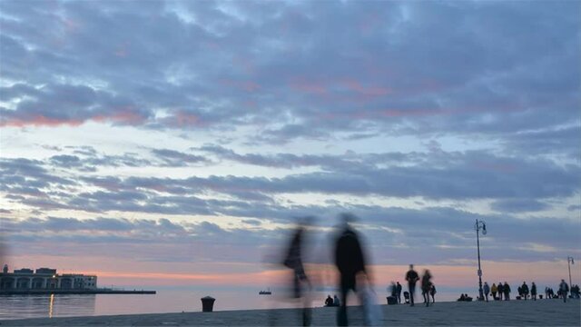 Trieste waterfront at sunset, people walking, time lapse, Italy
