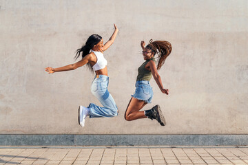 two young african girls jumping happy - Powered by Adobe