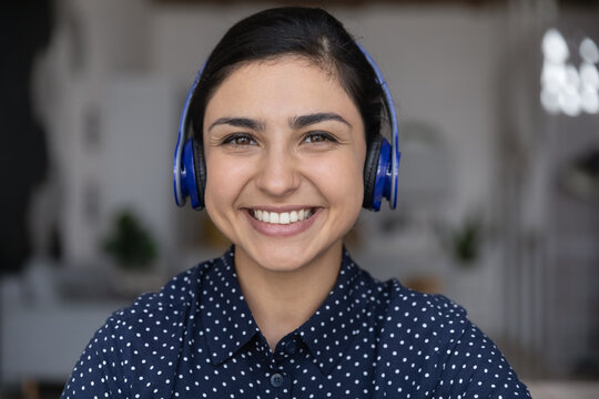 Close up portrait of happy beautiful Indian girl in headphones, young woman in headset looking at camera, webcam, smiling. Video call screen view heads hot of millennial support center employee