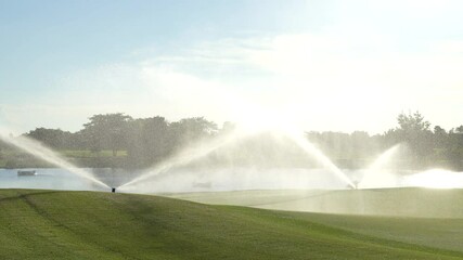 Automatic high-pressure water sprinkler at the golf course watering the grass