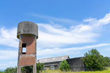 Old wooden and asbestos barracks and brick water tower remains on Motuihe Island in Hauraki Gulf.