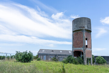 Fototapeta na wymiar Old wooden and asbestos barracks and brick water tower remains on Motuihe Island in Hauraki Gulf