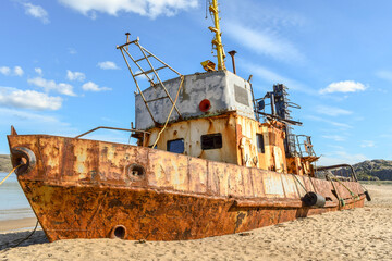 An old rusty ship buried in the sand on the seashore in northern Russia.
