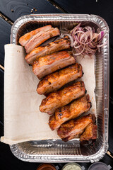 BBQ grilled ribs in a metal tray for delivery. Take out concept. In foil delivery box, food take away