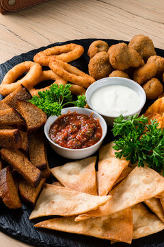 Deef Fried Fresh Beer Plate with Chicken Nuggets, Cheese Fingers, Onion Rings, Sauce on wood table.