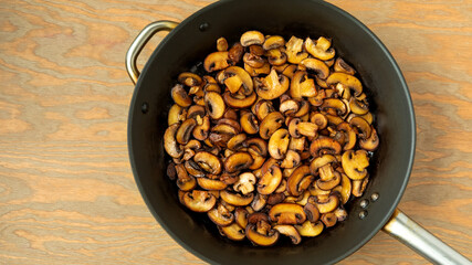 Pan-fried Champignon mushrooms on a frying pan. Brown edible fungi slices prepared.