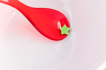 red spoon with green star in front of white background