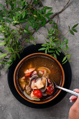 Hand holding a spoon with a shrimp and fish, Seafood Diet soup