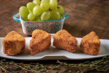 Camembert cheese fried in portions and presented with a bunch of grapes.