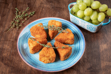 Camembert cheese fried in portions and presented with a bunch of grapes.