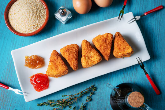 Fried Camembert cheese in portions with marmalade together with the ingredients used, breadcrumbs, oil and eggs.