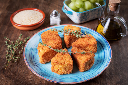 Fried camembert cheese in portions with breadcrumbs, salt, oil and grapes.