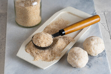 Psyllium husk on spoon soluble fiber supplement and raw bread or buns balls made of it before cooking. Superfood for healthy, lowers cholesterol, eases constipation. Keto, paleo low carb diet