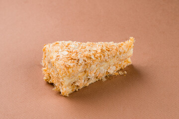Cake Napoleon of puff pastry and custard bakery. Closeup on brown background
