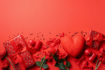 Valentines Day gifts, roses and candles on red backdrop, copy space