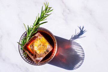 alcoholic cocktail negroni with a block of ice on a light background with a shadow