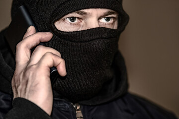 A criminal in a black balaclava and a hoodie in the dark. The concept of crime growth, robbery and...