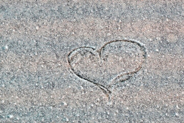 Heart drawn by the hand of a man on a marble wall in a blue close-up.  Icy stone wall with scratched heart